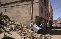 Dos ciudadanos intentan salvar el mobiliario de una casa derruida por el terremoto.