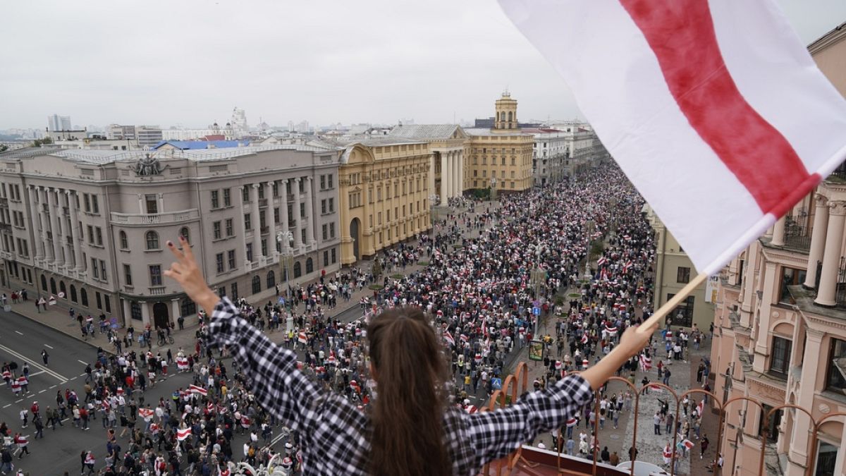 FILE A woman waves an old Belarusian national flag standing on the roof as Belarusian opposition supporters march to Independence Square in Minsk, Belarus, on 23/08/2020.