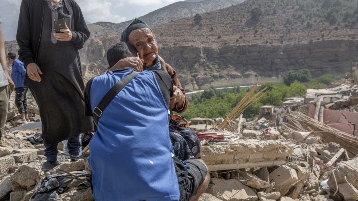 Спасатель утешает женщину, потерявшую членов своей семьи среди обломков разрушенных зданий после смертоносного землетрясения в Марокко