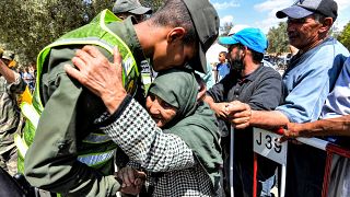 أحد أفراد القوات المساعدة المغربية يحتضن امرأة مسنة وصلت لتلقي مساعدات الإغاثة في حالات الكوارث من مركز التوزيع
