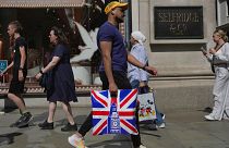 People walk along a street in a shopping district in central London, Tuesday, Aug. 22, 2023.