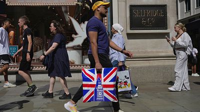 People walk along a street in a shopping district in central London, Tuesday, Aug. 22, 2023.