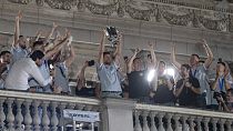 Novak Djokovic, center, holds the U.S. Open trophy in his hands as he makes a surprise appearance on the balcony of Belgrade's city hall
