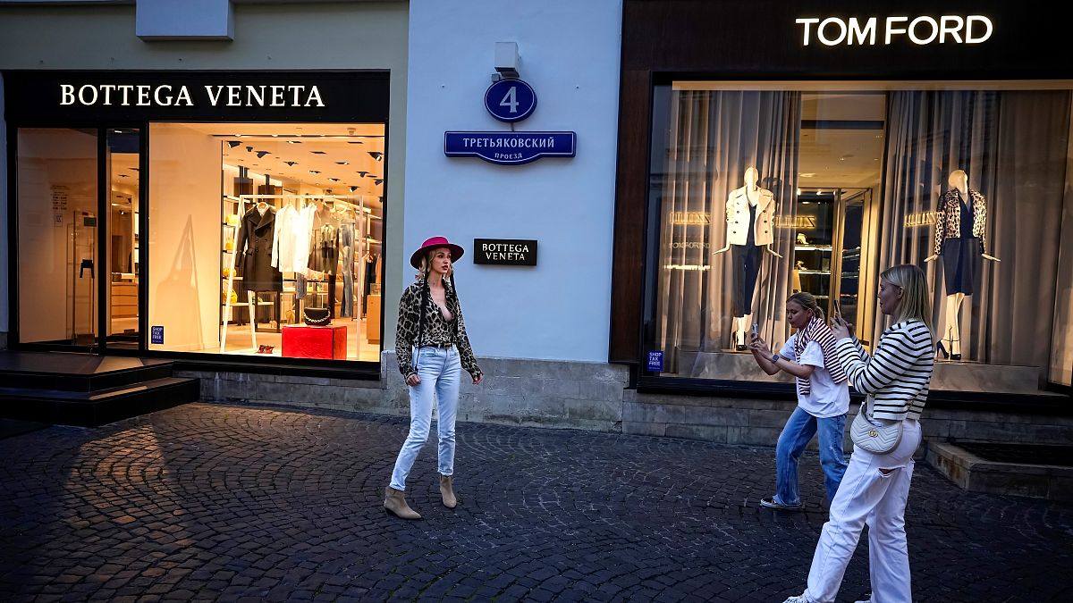 Transeuntes posam à porta de boutiques de luxo no centro de Moscovo, apesar das sanções e da guerra. 21 de agosto de 2023.