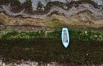 Гребная лодка стоит у прошлогодней линии воды на озере Преспа в деревне Стенье, Северная Македония, 6 сентября 2023 г. 