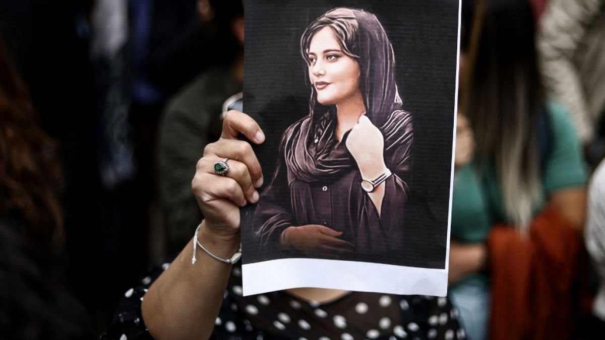 Una donna mostra la foto di Mahsa Amini 