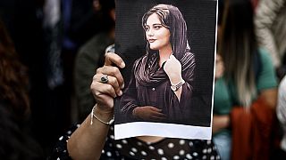 Una donna mostra la foto di Mahsa Amini