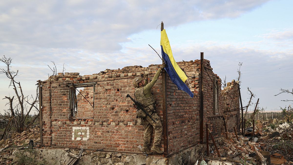 Un soldato issa la bandiera ucraina