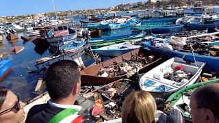 La primera ministra de Italia, Giorgia Meloni, contempla pateras vacías en el puerto de Lampedusa.