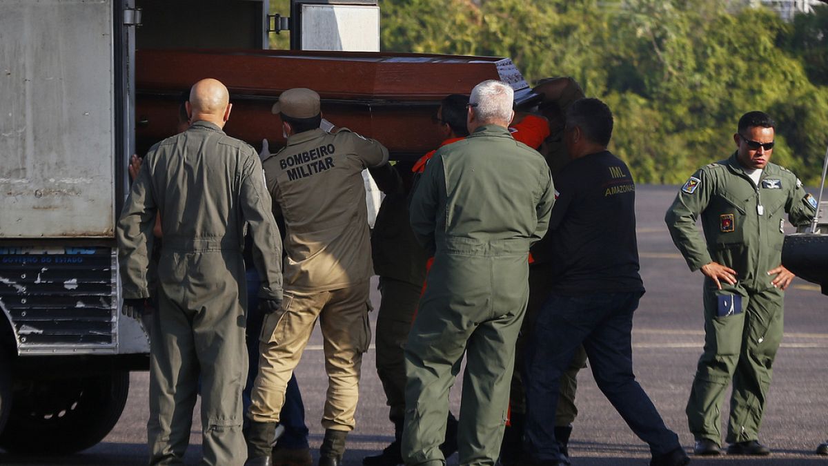 Operarios bajan un féretro con uno de los cuerpos de las víctimas del accidente de avión en Amazonas.
