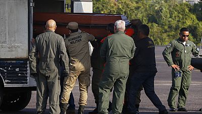 Operarios bajan un féretro con uno de los cuerpos de las víctimas del accidente de avión en Amazonas.