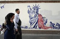 Passanten in Teheran laufen an eine einem antiamerikanischen Wandgemälde vorbei