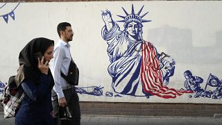 Passanten in Teheran laufen an eine einem antiamerikanischen Wandgemälde vorbei