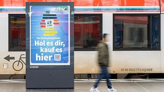 A man passes by an advertising for the Deutschlandticket (Germany Ticket) at a train station in Frankfurt, Germany, Monday, May 1, 2023.