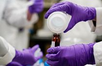 A water researcher pours a sample into a glass container for experimentation as part of drinking water and PFAS research at the US Environmental Protection Agency.