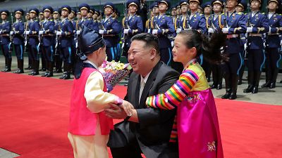 طفلان يعانقان زعيم كوريا الشمالية كيم جونغ أون في محطة قطارات بيونغ يانغ بعد عودته من زيارة إلى روسيا