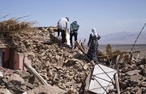 سكان يمشون فوق ركام بيتهم الذي دمره الزلزال في قرية تافغغت الجبلية قرب مراكش
