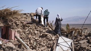 سكان يمشون فوق ركام بيتهم الذي دمره الزلزال في قرية تافغغت الجبلية قرب مراكش