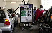 People fill up their tank at a gas station where placards read "No unleaded oil" and "Filling up jerry cans is forbidden", Wednesday, Oct. 12, 2022 in Cachan, outside Paris.
