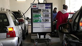 People fill up their tank at a gas station where placards read "No unleaded oil" and "Filling up jerry cans is forbidden", Wednesday, Oct. 12, 2022 in Cachan, outside Paris.