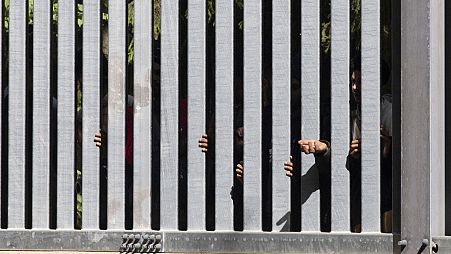 Members of a group of some 30 migrants seeking asylum are seen in Bialowieza, Poland, on May 28, 2023 across a wall that Poland has built on its border with Belarus