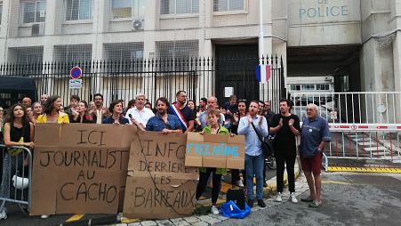 Protesters hold placards reading 'information behind bars' and 'journalist in jail here' as they demonstrate in front of the police headquarters in Marseille.