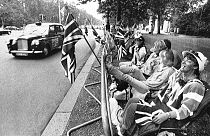 FILE - Potential spectators get into their early positions along the Mall, the wide road running from Buckingham Palace in London, July 22, 1986.
