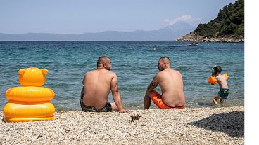 Cooling off by the sea Two men enjoy the pleasant coolness on a beach Manussa Beach on the Greek peninsula of Sithonia