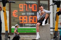 شاب يجلس بجوار شاشة تعرض أسعار صرف العملات من الدولار الأمريكي إلى الروبل الروسي في سانت بطرسبرغ - روسيا. 2023/07/06