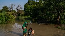 امرأة وابنتها تسيران وسط مياه الفيضان في نيودلهي - الهند. 2022/09/28