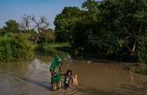 امرأة وابنتها تسيران وسط مياه الفيضان في نيودلهي - الهند. 2022/09/28