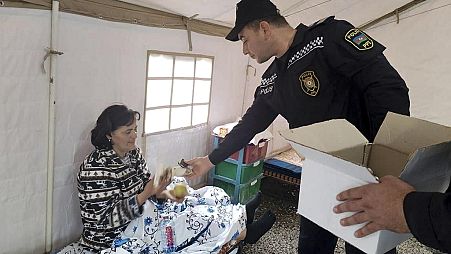 In this photo released by the Azerbaijani Interior Ministry press service on Friday, Sept. 22, 2023, an Azerbaijani police officer gives food to an ethnic Armenian woman.