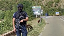 Agente da polícia do Kosovo vigia estrada perto da aldeia de Banjska, no norte do Kosovo, no domingo.