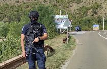 Um agente da polícia do Kosovo vigia a estrada perto da aldeia de Banjska, 55 quilómetros ao norte da capital, Pristina. 24 de setembro de 2023.