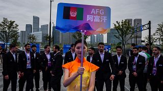 A volunteer holds up country's sign for Afghan men's only team during a welcoming ceremony at the 19th Asian Games in Hangzhou, China on Wednesday