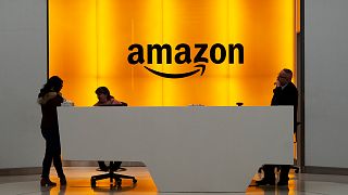 FILE - People stand in the lobby for Amazon offices in New York