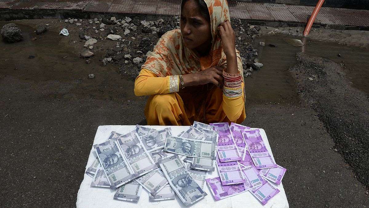 Hintli bir kadın 8 Haziran 2017 tarihinde Haydarabad'da bir caddede üzerinde Hindistan para birimi 500 ve 2000 rupilik banknotların resimlerinin basılı olduğu cüzdanları satıyor.