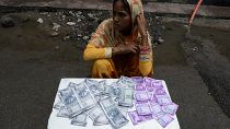 An Indian woman sells wallets printed with the images of Indian currency 500 and 2000 rupee notes on a street in Hyderabad on June 8, 2017.