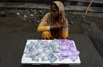 Hintli bir kadın 8 Haziran 2017 tarihinde Haydarabad'da bir caddede üzerinde Hindistan para birimi 500 ve 2000 rupilik banknotların resimlerinin basılı olduğu cüzdanları satıyor.
