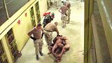  صورة حصلت عليها صحيفة واشنطن بوست ونشرت يوم  6 مايو/أيار 2004، تظهر عسكريين أمريكيين مع معتقلين عراة مقيدين ببعضهم البعض على الممشى أمام السجناء الآخرين في سجن أبو غريب في بغ