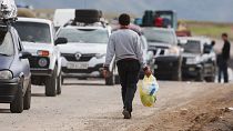 A refugee holding food and water walks along the queue of vehicles near the border town of Kornidzor, arriving from Nagorno-Karabakh