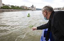 A man throws a flower into River Danube from a ship during an ecumenical commemoration marking the second anniversary of a fatal boat accident on the River Danube, in Budapest