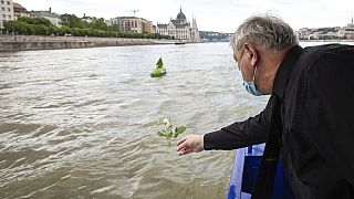 A man throws a flower into River Danube from a ship during an ecumenical commemoration marking the second anniversary of a fatal boat accident on the River Danube, in Budapest