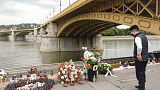 Un hombre junto a velas y flores colocadas sobre el río Danubio durante una ceremonia en memoria de las víctimas, un año después del accidente del barco.
