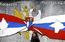 FILE - A woman walks by graffiti showing the Serbian flag, left, and Russian flags with maps of Kosovo and Crimea in northern Kosovo, 15/12/2018. 