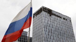 Orosz zászló egy dróntámadásban megrongálódott moszkvai irodaépület előtt 2023. július 24-én.