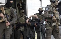 Miembros de la policía de Kosovo de la Unidad de Intervención Especial escoltan a uno de los pistoleros serbios arrestados fuera del tribunal después del tiroteo en Kosovo.