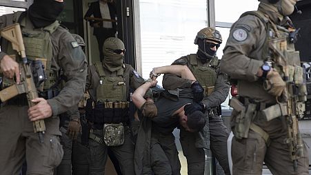 A koszovói rendőrség különleges beavatkozási egységének tagjai kikísérik a bíróságról az egyik letartóztatott szerb fegyverest a koszovói lövöldözés után Pristinában