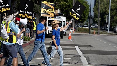 Screenwriters Meagan Daine, right, and Craig Stiles join in support SAG-AFTRA picketers outside the gates of Warner Bros. studios in California, Tuesday, Sep. 26, 2023