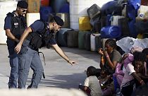 A police officer plays with a migrant child blowing soap bubbles in the port of the Sicilian island of Lampedusa, southern Italy, Monday, Sept. 18, 2023.